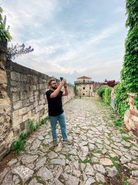 Bir adam kalede bir bakış açısıyla fotoğraf çekiyor. Akıllı telefon kameralı bir turist..