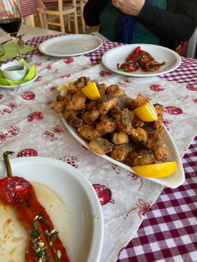 Balkanlarda sıcak bir yemek için hazırlanmış bir masa. Limon dilimleriyle süslenmiş kızarmış balık. Kırmızı biber ve bir bardak şarap büyüleyici bir kırsal restoranda akşam yemeği sahnesini tamamladı..