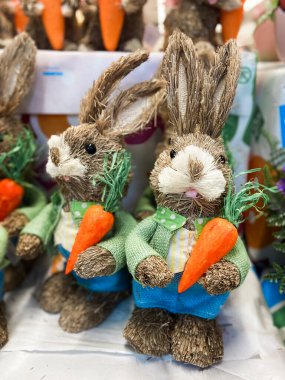 İki sevimli saman tavşanı, büyüleyici bahar kıyafetleri içinde neşeli ve kaprisli bir sahne yaratarak canlı havuçları tutarlar. El yapımı figürler bir insanın neşesini ve masumiyetini somutlaştırır.