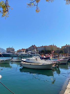 Tekneler sakin bir limanda, berrak mavi bir gökyüzünün altında, rıhtımı kaplayan büyüleyici binaların altında nazikçe yüzerler. Kıyı yaşamının özü ve huzurlu rahatlama, seyahat, yolculuk ve yolculuk konsepti.