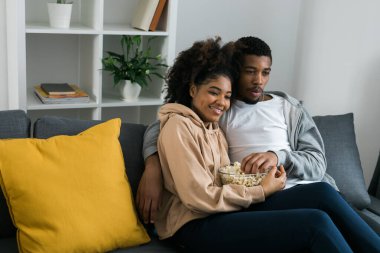 Afrika kökenli Amerikalı çift karı koca film izliyor. Aile eğlencesi, boş zaman, televizyon izlemek, dinlenmek. Rahatlamış bir adam ve kadın televizyon dizisi izliyorlar. Kanepede oturup yemek yiyorlar.