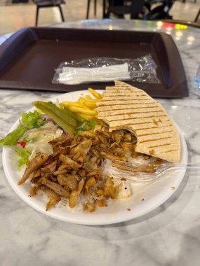 Tabakta shawarma, pilav, salata, turşu ve patates kızartması servis ediliyor. Gündelik yemek ve eğlence..