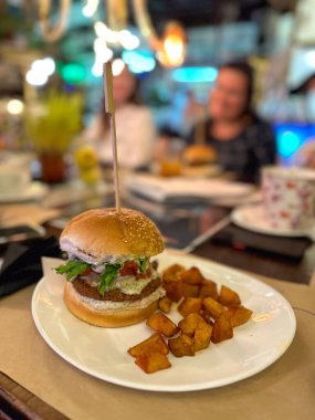 Taze malzemelerle sulu vejetaryen burger ve yanında çıtır patates küpleri. Hamburgerde alternatif bitki temelli et