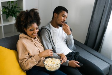 Afrika kökenli Amerikalı çift karı koca film izliyor. Aile eğlencesi, boş zaman, televizyon izlemek, dinlenmek. Rahatlamış bir adam ve kadın televizyon dizisi izliyorlar. Kanepede oturup yemek yiyorlar.