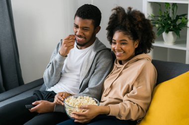 Afrika kökenli Amerikalı çift karı koca film izliyor. Aile eğlencesi, boş zaman, televizyon izlemek, dinlenmek. Rahatlamış bir adam ve kadın televizyon dizisi izliyorlar. Kanepede oturup yemek yiyorlar.