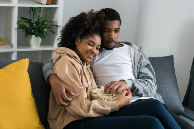 Afrika kökenli Amerikalı çift karı koca film izliyor. Aile eğlencesi, boş zaman, televizyon izlemek, dinlenmek. Rahatlamış bir adam ve kadın televizyon dizisi izliyorlar. Kanepede oturup yemek yiyorlar.