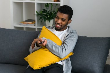 Neşeli kıvırcık saçlı, hafta sonu televizyon ya da film izlerken rahat bir kanepede dinlenen gündelik giysili Afro-Amerikan erkeği. Televizyon seti, çevrimiçi televizyon ve işletme