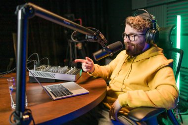 Canlı yayında gülümseyen bir milenyum adamıyla mikrofon, talk show ya da eğlence sunucusu olarak. Erkek içerik yaratıcısı ve ses veya sosyal kayıt için podcast sunucusunda mutlu.