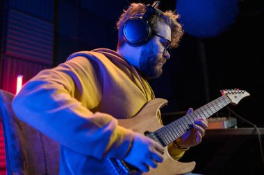 Gitarlı bir kayıt stüdyosunda şarkı söyleyen erkek vokalist. Erkek şarkıcı bir şarkı söylüyor ve gitar çalıyor. Ses kaydı ve müzik akışı kavramı