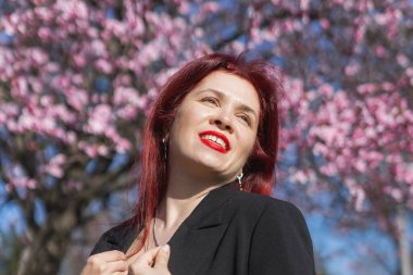 Etrafı çiçek açan ağaçlarla çevrili kiraz çiçekli kadın boşluğu kopyalıyor. Güzellik ve mevsimsel değişim ve bahar mevsimi konsepti