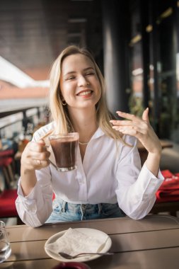 Güzel sarışın bir kadının portresi. Balkon kafeteryasında çay içip arkadaşlarıyla sohbet ediyor. Gülümseyen mutlu bir kadın kahve dükkanında dinleniyor.