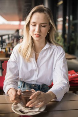 Sarışın kadın yazlık kafede sıcak çikolata içiyor. Lezzetli içecek ve mola.
