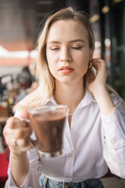 Sarışın kadın yazlık kafede sıcak çikolata içiyor. Lezzetli içecek ve mola.