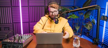 Canlı yayında gülümseyen bir milenyum adamıyla mikrofon, talk show ya da eğlence sunucusu olarak. Erkek içerik yaratıcısı ve ses veya sosyal kayıt için podcast sunucusunda mutlu.