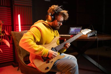 Erkek şarkıcı gitar çalıyor ve şarkı söylüyor. Kayıt stüdyosunda sahne alan bir adam. Müzik albümü kaydediliyor