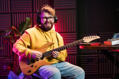 Müzik stüdyosunda elektro gitar çalan sakallı adam. Müzik sektöründe performans ve gösteri, müzik yayını ve kaydı