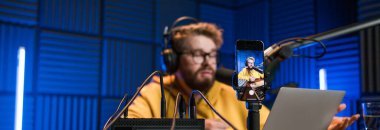 Canlı yayında gülümseyen bir milenyum adamıyla mikrofon, talk show ya da eğlence sunucusu olarak. Erkek içerik yaratıcısı ve ses veya sosyal kayıt için podcast sunucusunda mutlu.