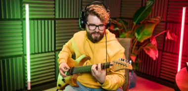 Müzik stüdyosunda elektro gitar çalan sakallı adam. Müzik sektöründe performans ve gösteri, müzik yayını ve kaydı