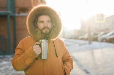 Soğuk kış kentsel caddesinde gün ışığında sıcak içkinin tadını çıkaran bir adam. Huzurlu yalnızlık ve kış şehri ortamında sabah rutini
