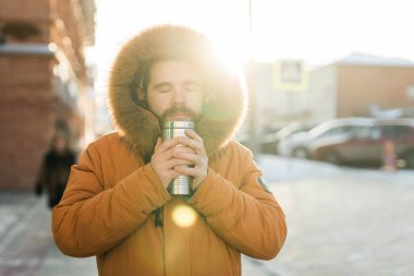 Adam soğuk kış sabahında sıcak içecekle ısınıyor. Mevsimsel şehir yaşam tarzı anlarında konfor, rutin ve yalnızlık