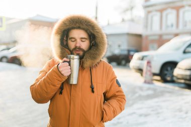 Adam soğuk kış sabahında sıcak içecekle ısınıyor. Mevsimsel şehir yaşam tarzı anlarında konfor, rutin ve yalnızlık
