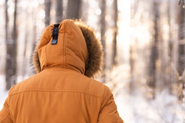 Güneşin doğuşunda, karlı ormanda ceketiyle yürüyen bir adam. Yalnızlık, yalnızlık ve kış doğasıyla bağlantı.