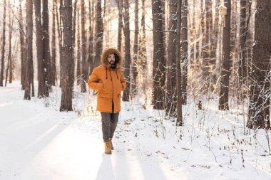 İnsan kış ormanlarında karlı yolda yürüyor. Farkındalık, mevsimsel değişim ve barışçıl bir açık hava anında doğayla uyum. Boşluğu kopyala.
