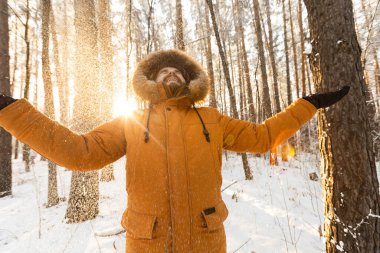 Adam kış ormanında taze karın tadını çıkarıyor. Huzurlu bir kar gününde neşe, özgürlük ve doğa ile bağlantı.