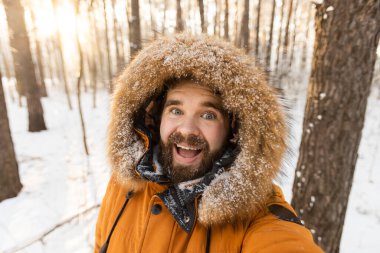 Orman yürüyüşü ve selfie çekmekten zevk alan heyecanlı bir adam. Kar mevsiminde neşe, özgürlük ve doğa ile bağlantı
