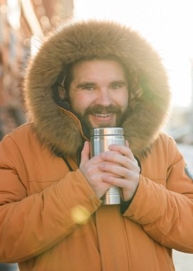 Soğuk kış kentsel caddesinde gün ışığında sıcak içkinin tadını çıkaran bir adam. Huzurlu yalnızlık ve kış şehri ortamında sabah rutini