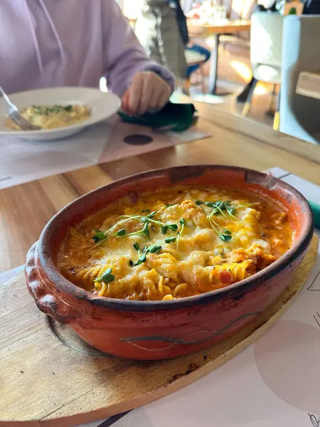 Ahşap tabakta kil tabakta servis edilen fırında makarna. Sıcaklık, gelenek ve sıcacık bir ortamda ev yapımı sıcak bir yemeğin rahatlığını taşır.