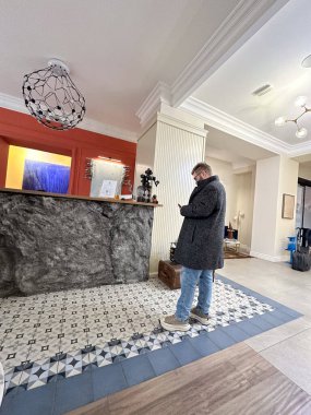 Otel resepsiyonunda akıllı telefon kullanan bir adam. Seyahat, kontrol süreci ve seyahatler sırasında modern yaşam tarzı.