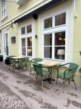 Sakin bir caddede boş masaları olan açık bir kafe. Kentsel yaşam tarzı, sosyal rutin ve rahat sokak kültürü.