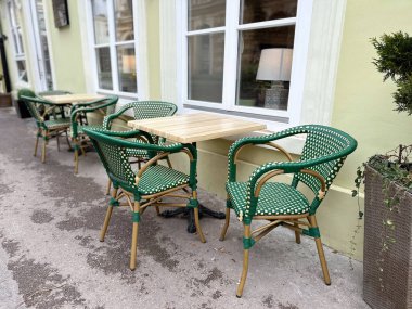 Sakin bir caddede boş masaları olan açık bir kafe. Kentsel yaşam tarzı, sosyal rutin ve rahat sokak kültürü.