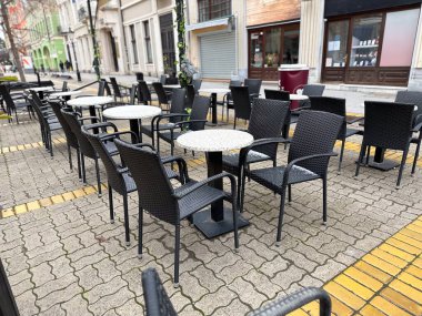 Boş kafeterya masaları ve sandalyeler sessiz bir şehir ortamında. Günlük yaşamda şehir rutini, boş zaman ve açık alan.