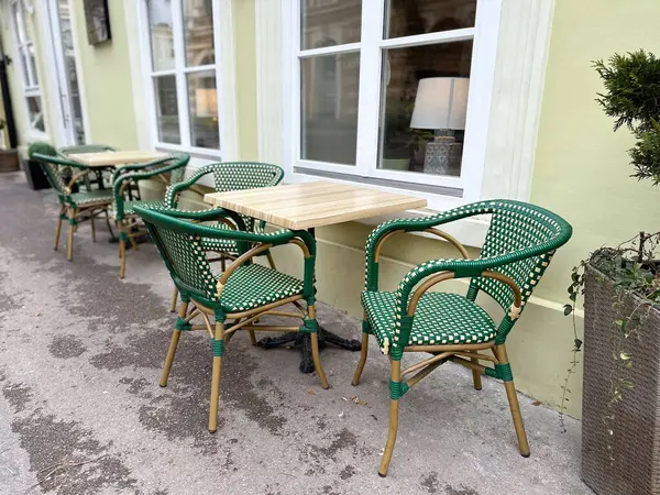 Sakin bir caddede boş masaları olan açık bir kafe. Kentsel yaşam tarzı, sosyal rutin ve rahat sokak kültürü.