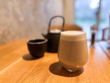 Sıcak bir kafede, ahşap bir masada sıcak bir içecek. Rahatlık, sabah ritüeli ve basit nesnelerle huzurlu bir yaşam tarzı..