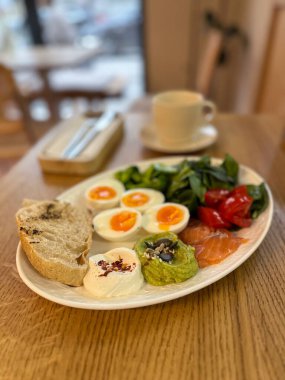 Tahta masada yumurta, somon ve sebzelerle dengeli kahvaltı. Sağlıklı beslenme, dikkatli rutin ve sabah enerji takviyesi.