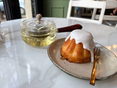 Sütlü tatlı ve kafedeki beyaz masada cam çaydanlık. Huzurlu bir tatil ve sıcak bir çay molası..