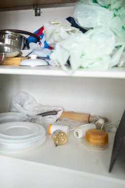 Rastgele nesneler, kablolar ve plastik poşetlerle dolu dağınık mutfak dolabı. Günlük hayatta dağınıklık ve düzensiz depolama alanı