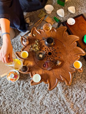 Bir kadın arkadaşlarıyla geleneksel çay seremonisi sırasında yaprak çayı hazırlar. Topluluk, farkındalık ve çay paylaşma ritüeli.