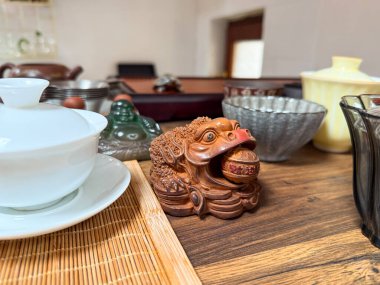 Geleneksel tören sırasında seramik kurbağa ve çay aksesuarları ahşap çay masasında. Çay pratiğinde ayin, uyum ve kültürel sembolizm..