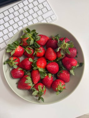 Klavyenin yanındaki masada taze çilekler var. Sağlıklı alışkanlıkları olan dijital yaşam tarzı.
