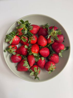 Beyaz arka planda bir kasede lezzetli kırmızı çilekler.