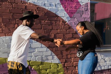 Afrika kökenli Amerikalı çift renkli duvarın yanında açık havada dans ediyor. Aşk, neşe, hareket ve şehir yaşam tarzı kavramı. Bachata, salsa, kizomba dansı.