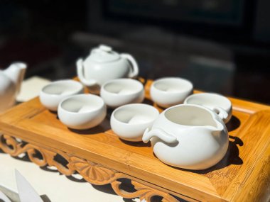 Ahşap tepside beyaz teaware seti. Porselen kaseler ve sürahiler geleneksel çay hazırlığı için düzenlenmiştir.