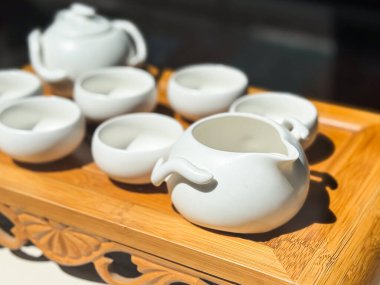 Ahşap tepside beyaz teaware seti. Porselen kaseler ve sürahiler geleneksel çay hazırlığı için düzenlenmiştir.