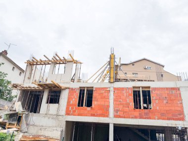 Beton ve tuğla bina etkin inşaat altında. Çerçeve, sütunlar ve destek kirişleri devam eden yapısal gelişmeyi gösteriyor.