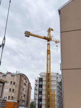 Yerleşim alanının üzerinde yükselen bir vinç. Büyümeyi ve modernleşmeyi sembolize eden dikey altyapı gelişimi