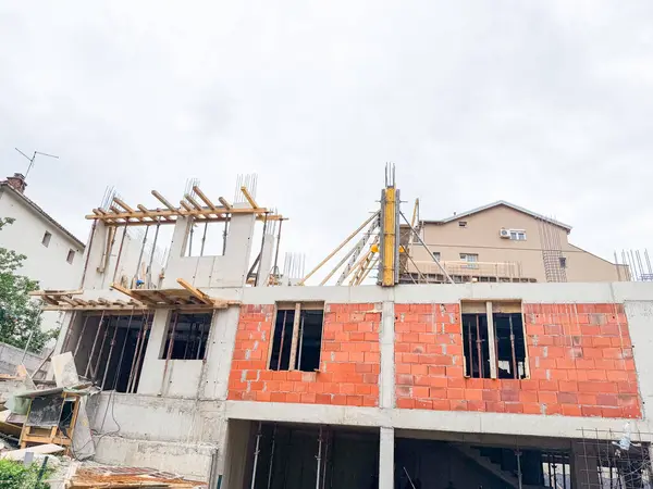 Beton ve tuğla bina etkin inşaat altında. Çerçeve, sütunlar ve destek kirişleri devam eden yapısal gelişmeyi gösteriyor.